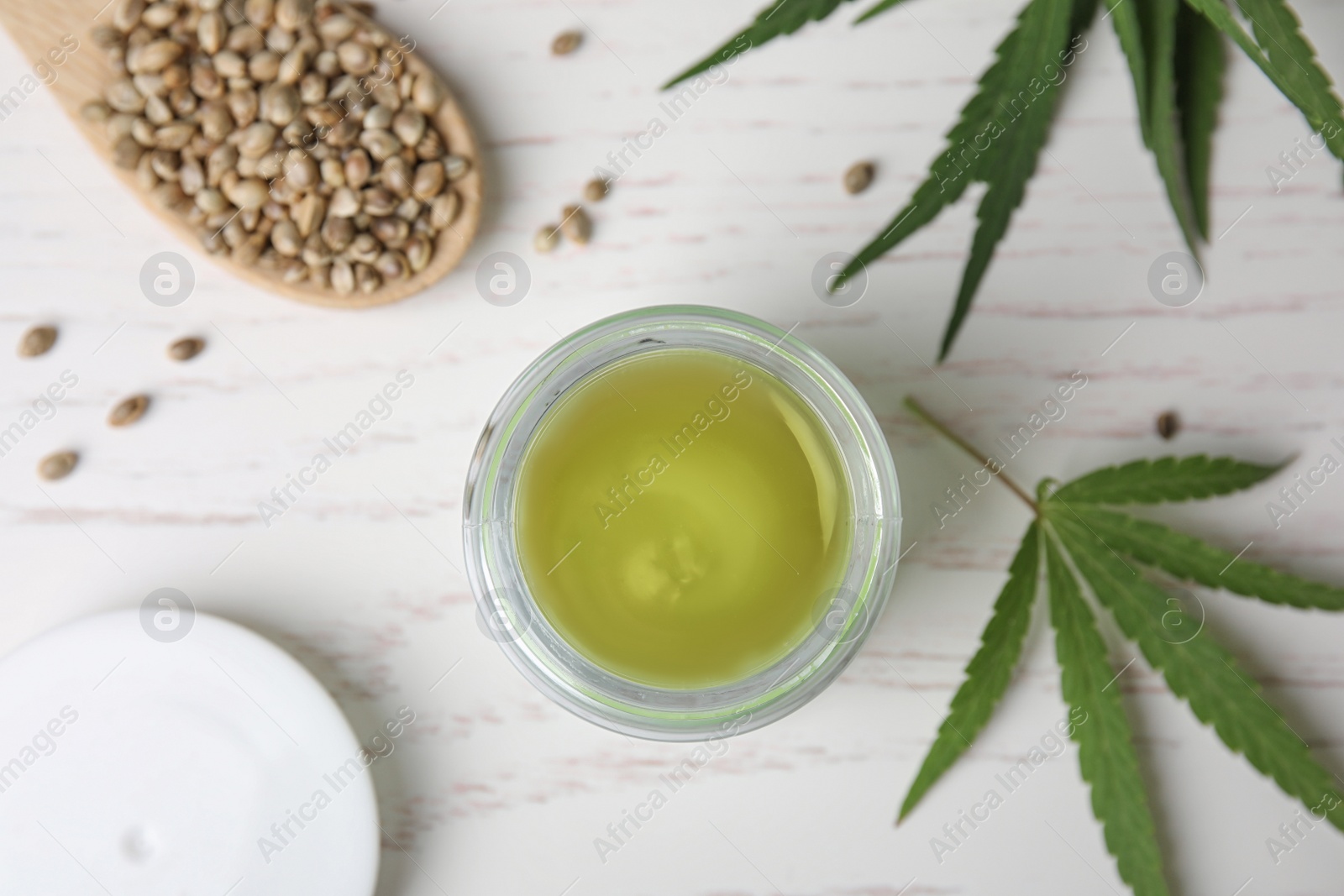 Photo of Jar of hemp cream and seeds on white wooden table, flat lay. Organic cosmetics