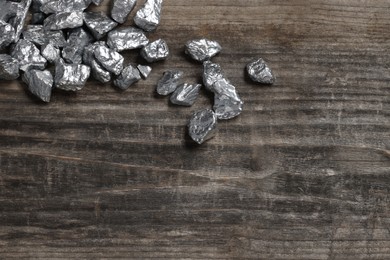 Photo of Pile of silver nuggets on wooden table. Space for text