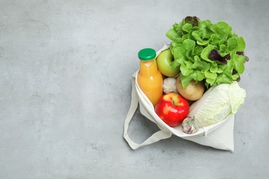 Photo of Bag with fresh vegetables, apples and bottle of juice on color background, top view. Space for text