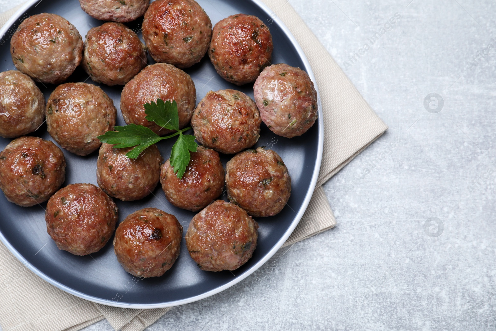 Photo of Tasty cooked meatballs with parsley on light grey table, flat lay, Space for text