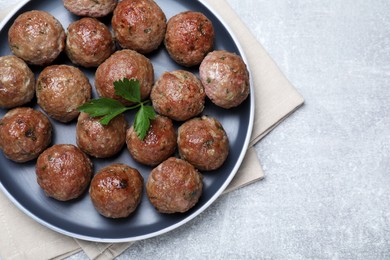 Photo of Tasty cooked meatballs with parsley on light grey table, flat lay, Space for text