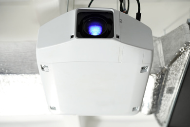 Photo of Modern video projector hanging on ceiling, closeup