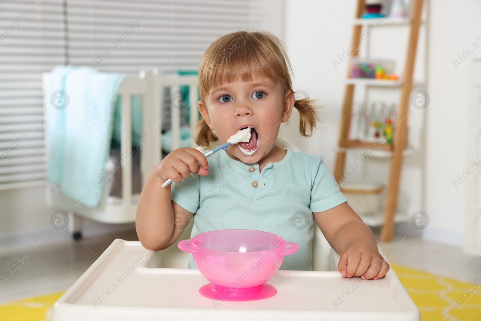 Photo of Cute little child eating tasty yogurt with spoon at home