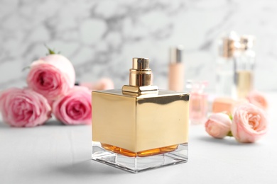 Bottle of perfume and roses on table against marble background