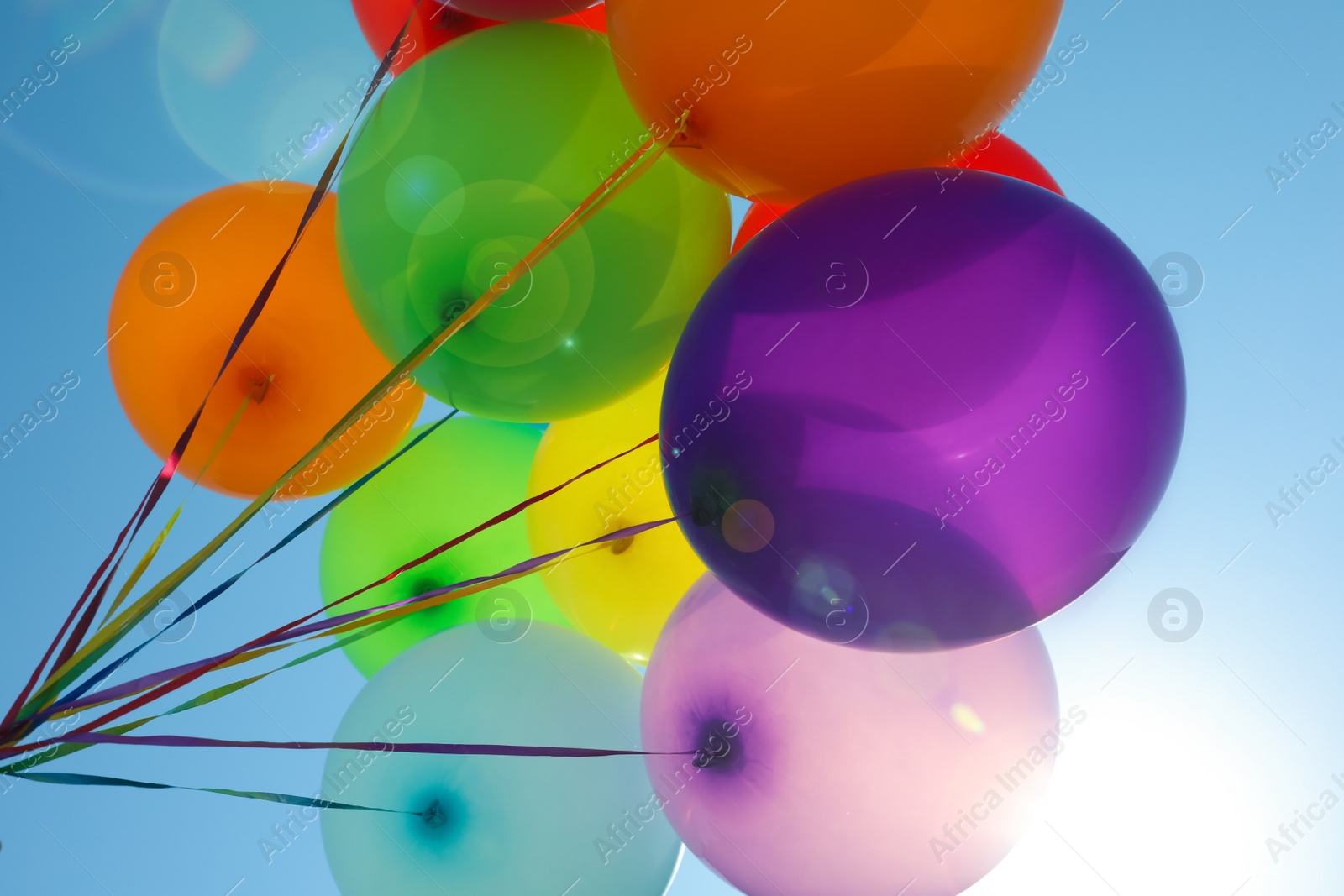 Photo of Bunch of colorful balloons against blue sky, low angle view