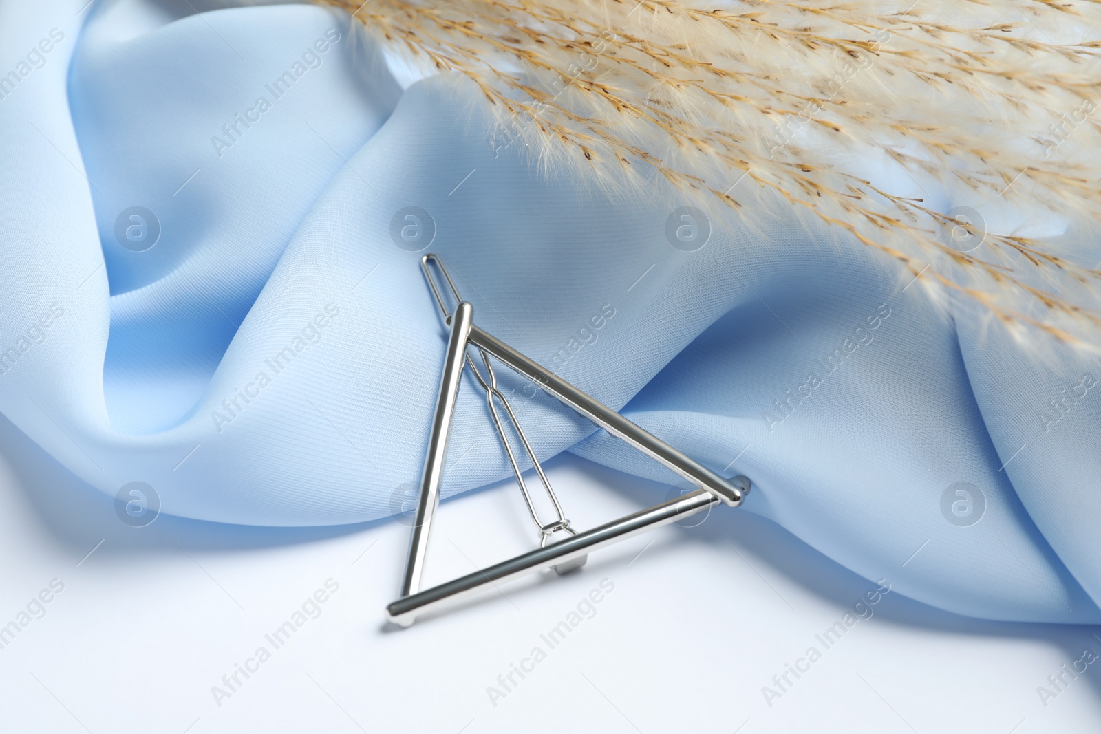 Photo of Stylish hair clip and light blue fabric on white table