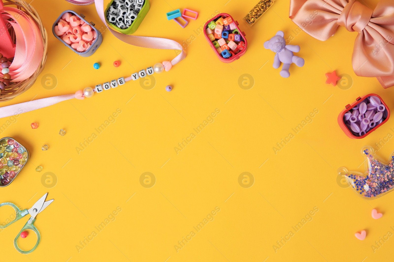 Photo of Kid`s handmade jewelry kit. Colorful beads, ribbon, bow and different supplies on orange background, flat lay. Space for text