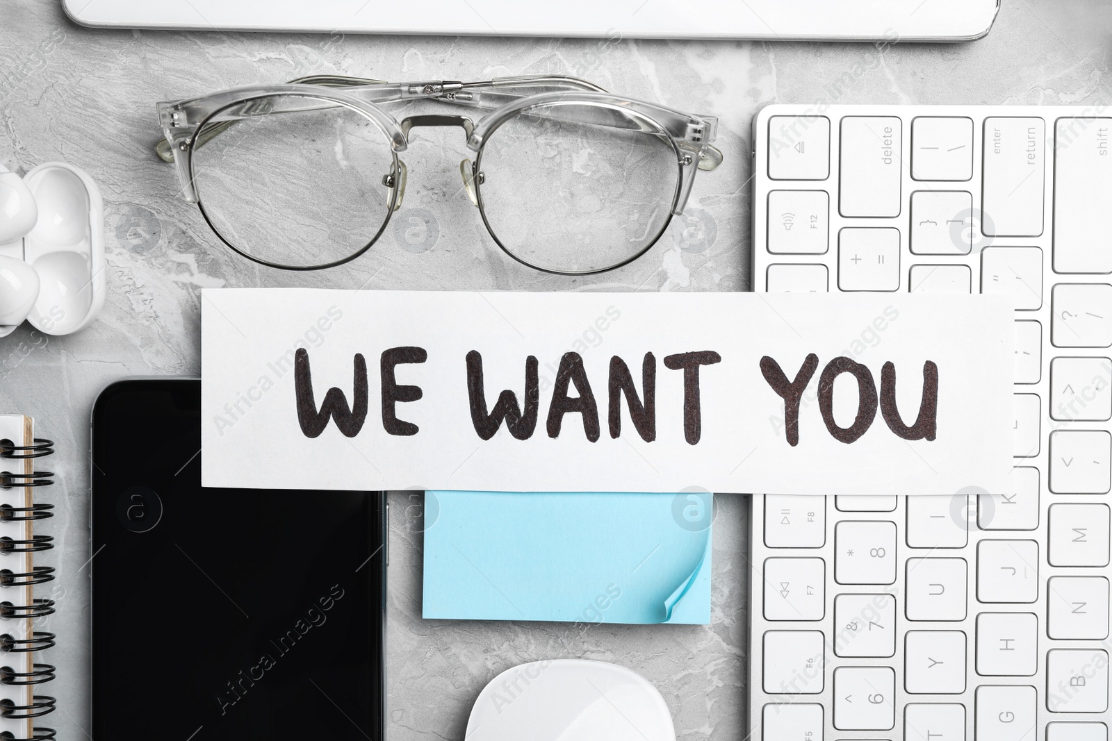 Photo of Flat lay composition with words WE WANT YOU, computer keyboard and smartphone on light grey marble table. Career concept