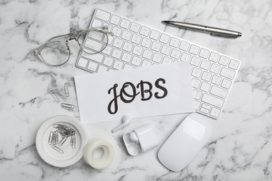 Flat lay composition with word JOBS, computer keyboard and stationery on white marble table. Career concept