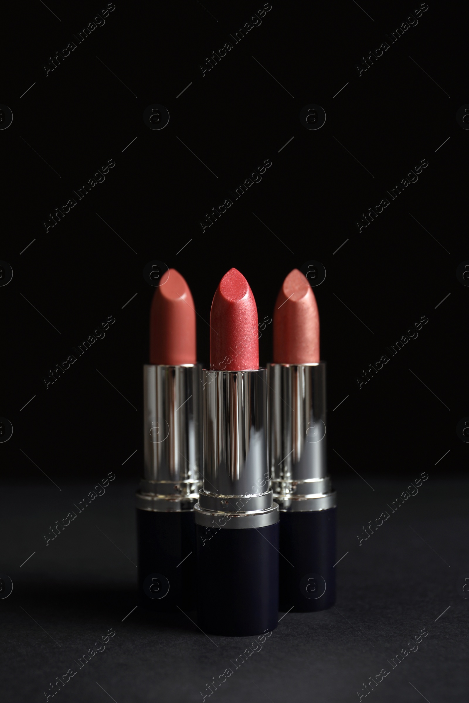 Photo of Different lipsticks on table against dark background. Space for text