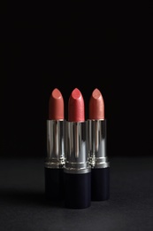 Photo of Different lipsticks on table against dark background. Space for text