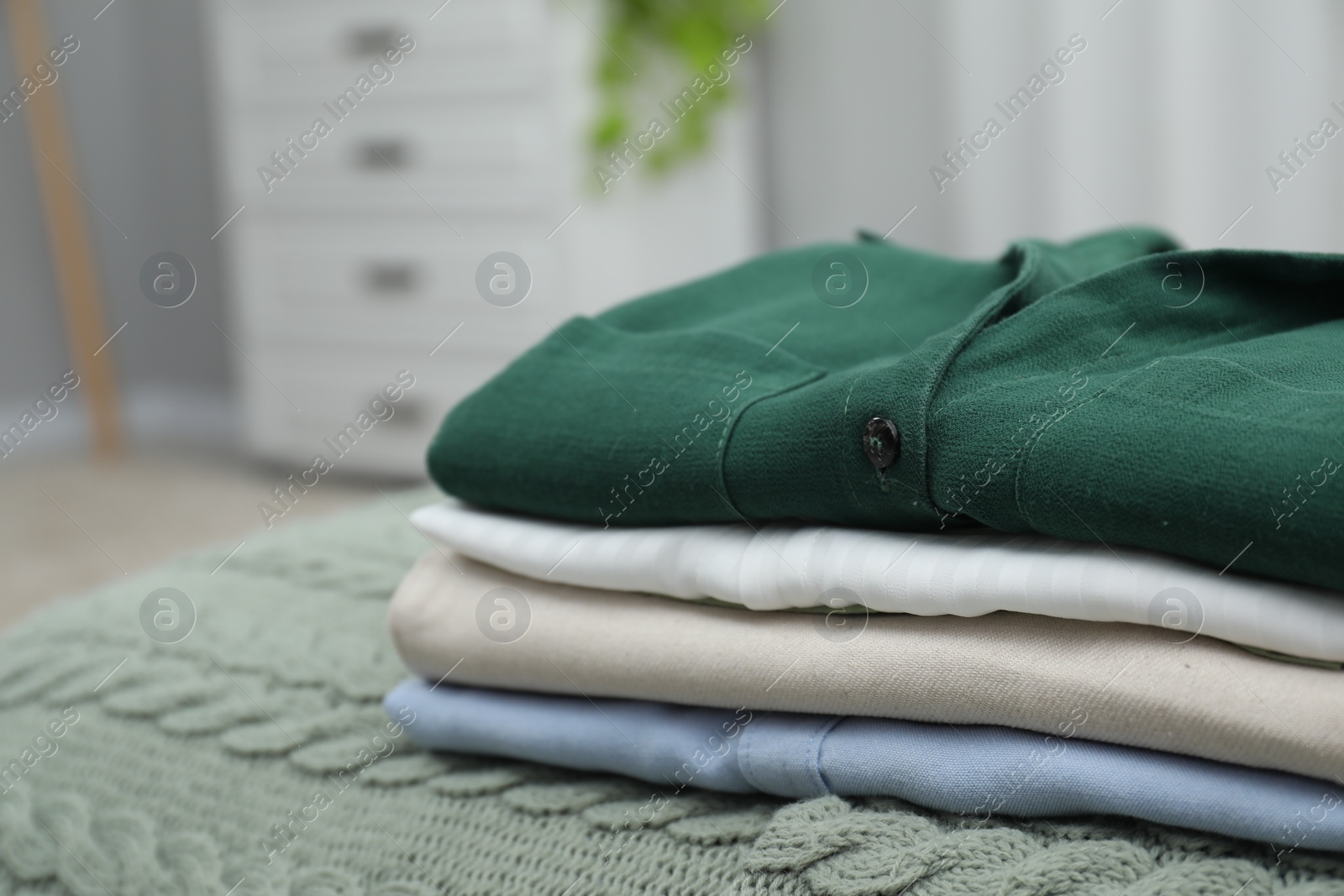 Photo of Sorting and organizing. Stack of different folded clothes on bed indoors, space for text