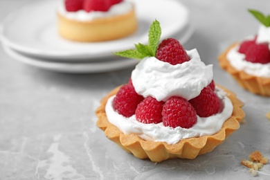 Photo of Tarts with raspberries on marble table, closeup. Delicious pastries