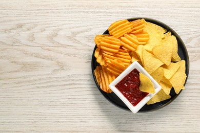 Photo of Tasty tortilla and ridged chips with ketchup on white wooden table, top view. Space for text