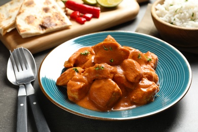 Photo of Delicious butter chicken served on grey table. Traditional indian Murgh Makhani