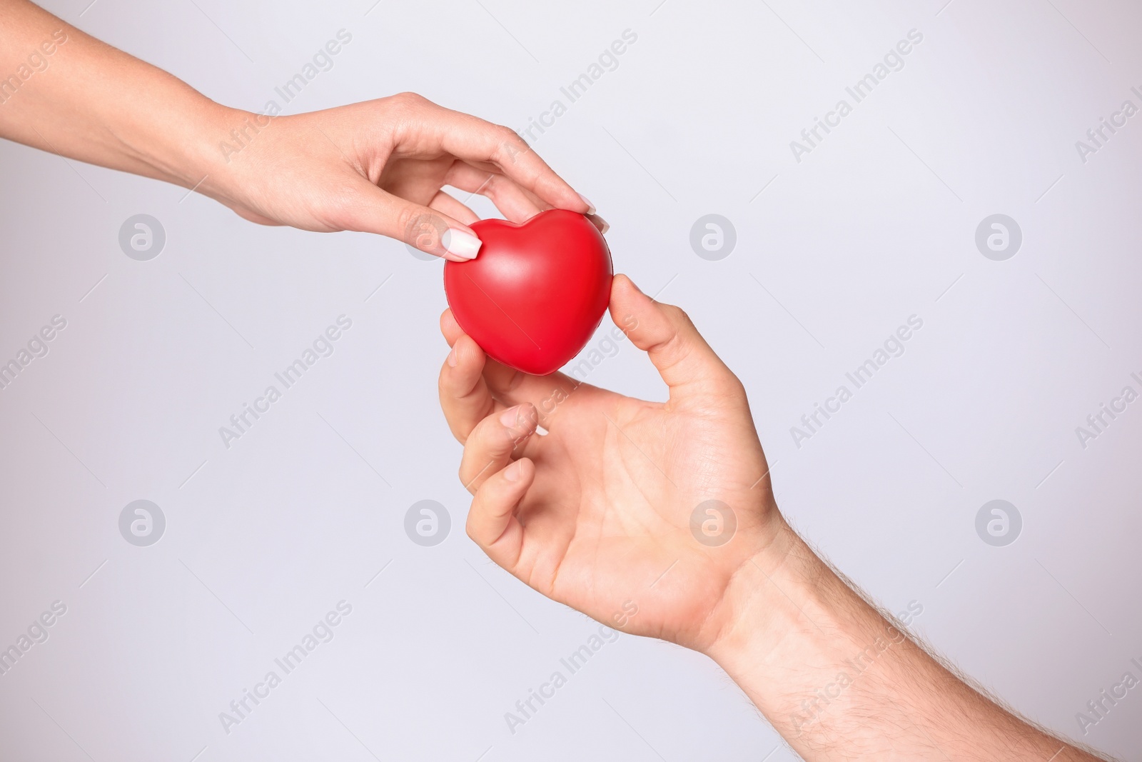 Photo of Woman giving red heart to man on white background, closeup. Donation concept