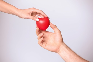 Woman giving red heart to man on white background, closeup. Donation concept