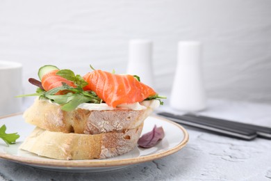 Tasty bruschetta with salmon, cucumber and herbs on white textured table, closeup. Space for text