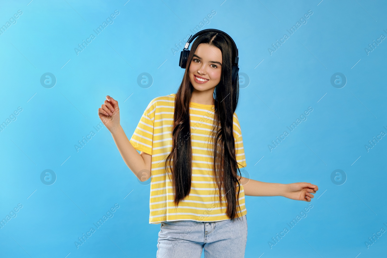 Photo of Teenage girl listening music with headphones on light blue background