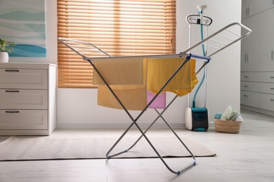 Clean laundry hanging on drying rack indoors