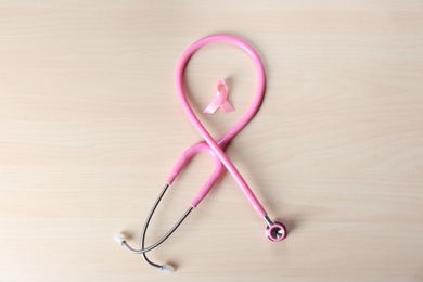 Photo of Pink ribbon with stethoscope on wooden background. Breast cancer concept