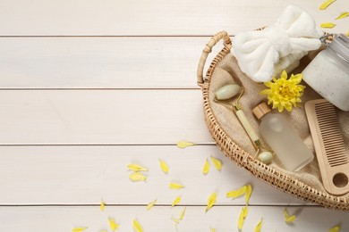 Photo of Spa gift set with different products in wicker basket on white wooden table, flat lay. Space for text
