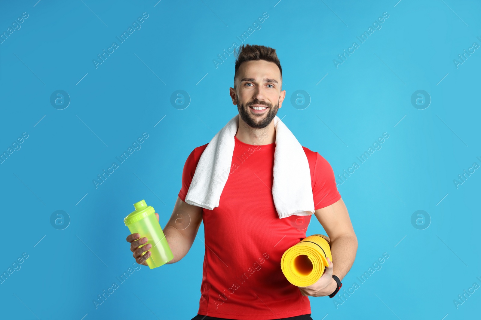 Photo of Beautiful man with yoga mat, towel and shaker on turquoise background