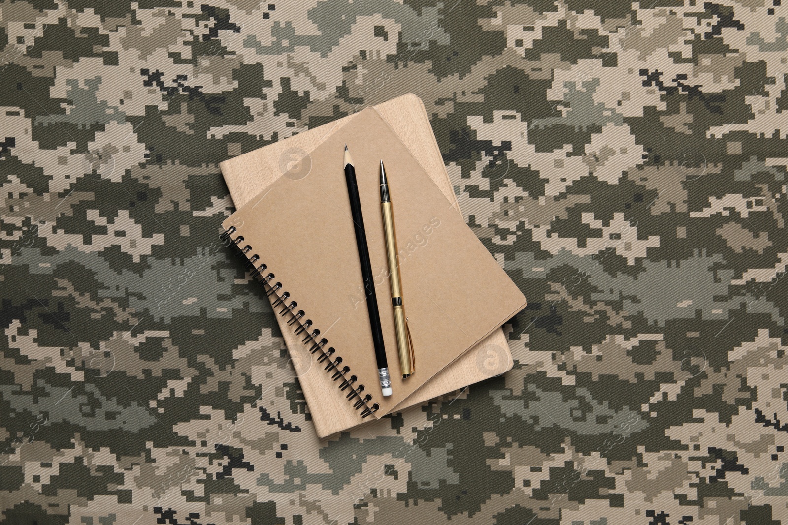 Photo of Notebooks, pen and pencil on camouflage background, top view. Military education