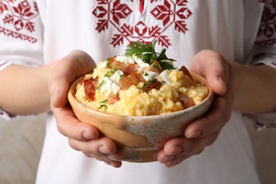 Photo of Woman holding bowl of delicious traditional Ukrainian banosh, closeup