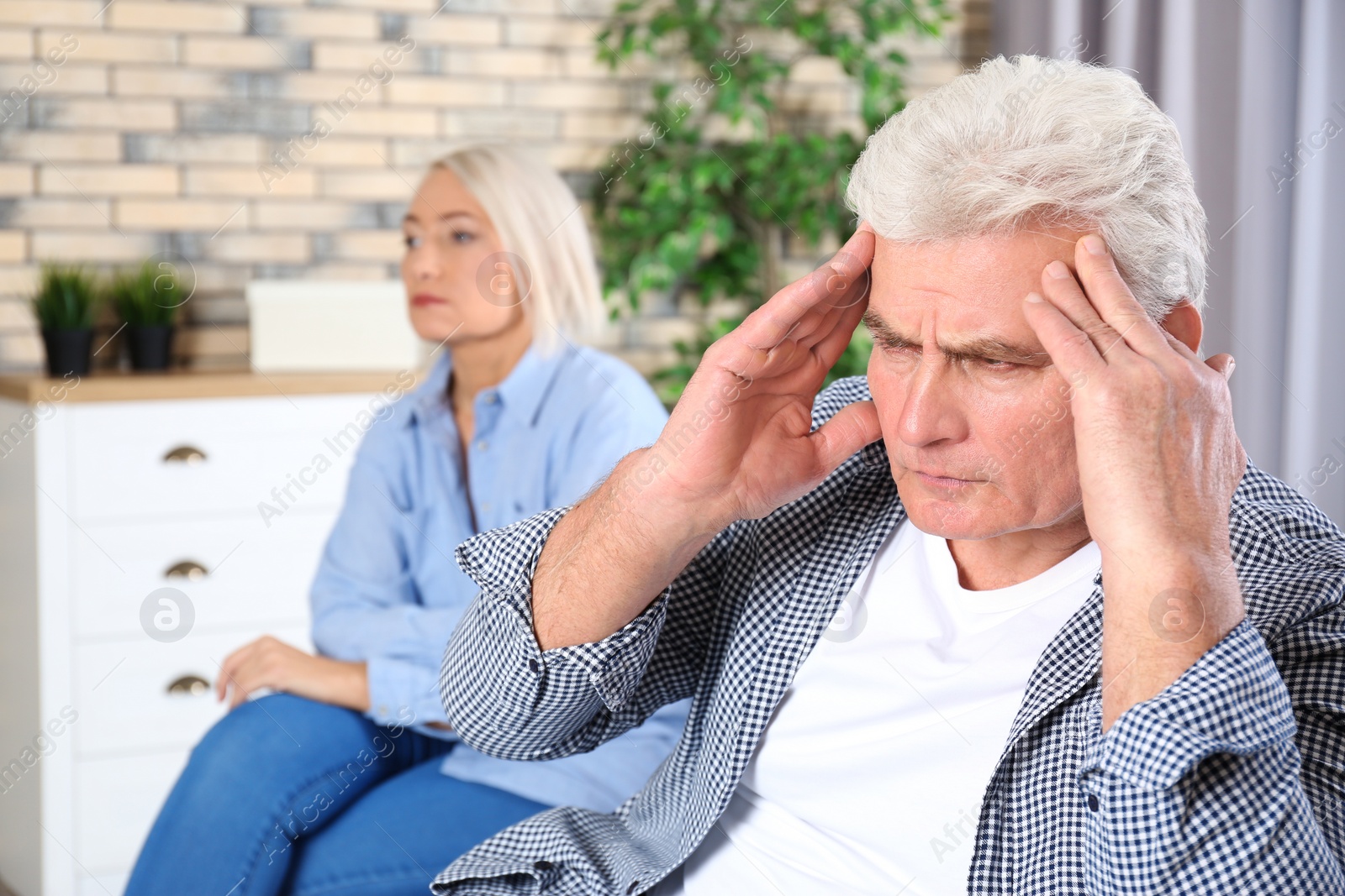 Photo of Mature couple with relationship problems ignoring each other after conflict in living room