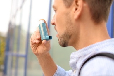 Photo of Man using asthma inhaler outdoors, closeup. Health care