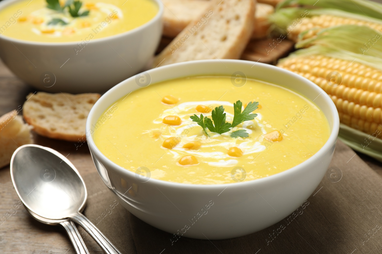 Photo of Delicious creamy corn soup served on wooden table, closeup