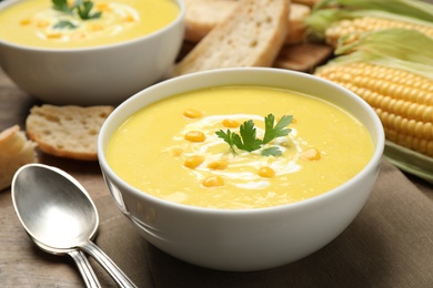 Photo of Delicious creamy corn soup served on wooden table, closeup