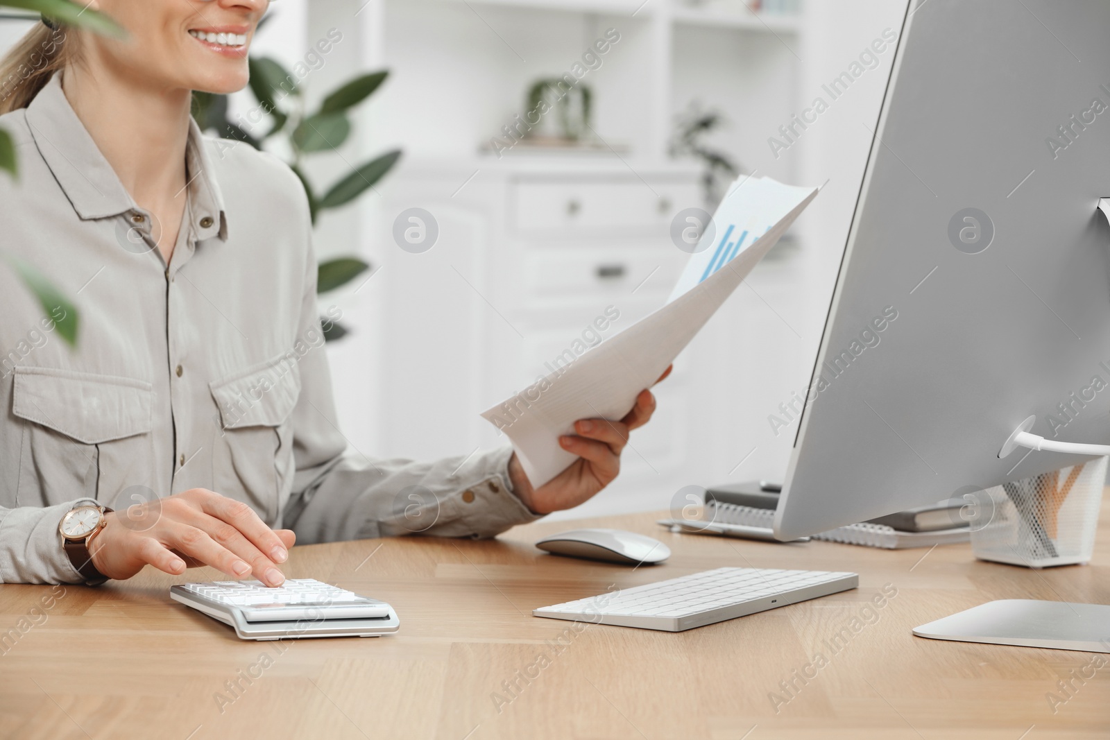 Photo of Professional accountant using calculator at wooden desk in office, closeup