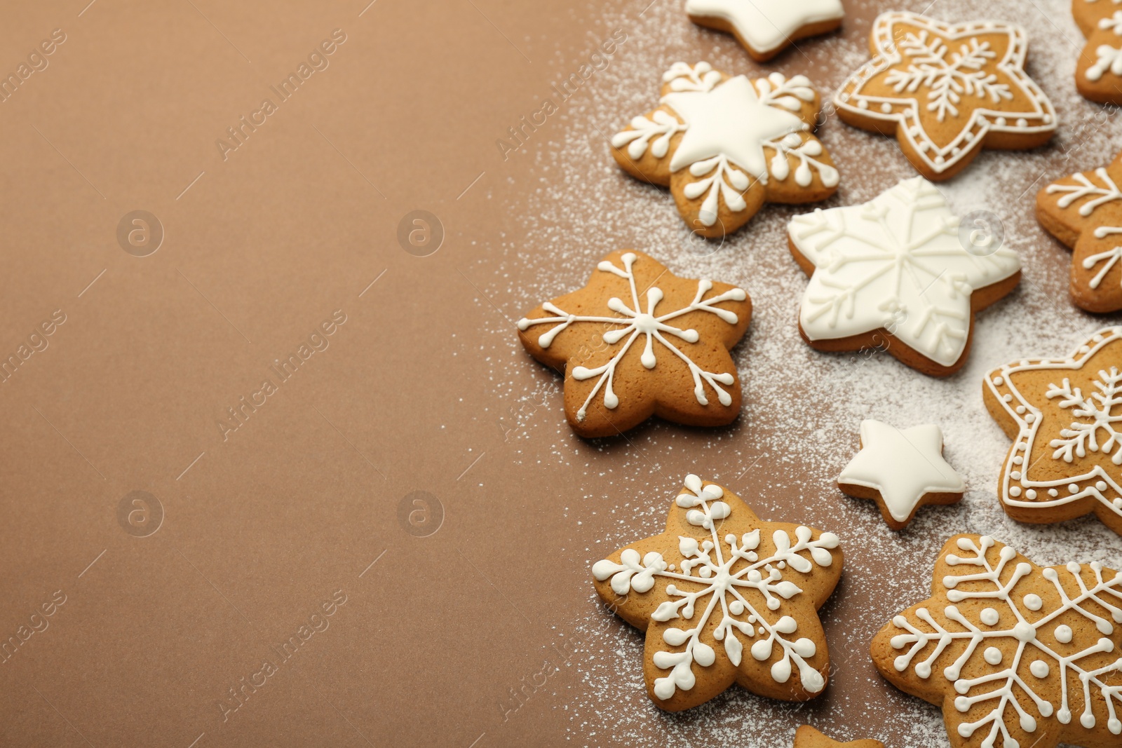 Photo of Tasty Christmas cookies with icing and powdered sugar on brown background. Space for text