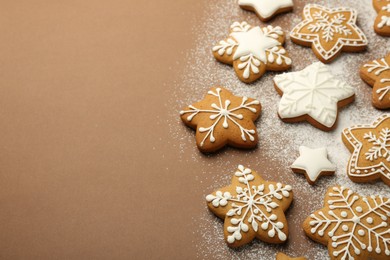 Photo of Tasty Christmas cookies with icing and powdered sugar on brown background. Space for text