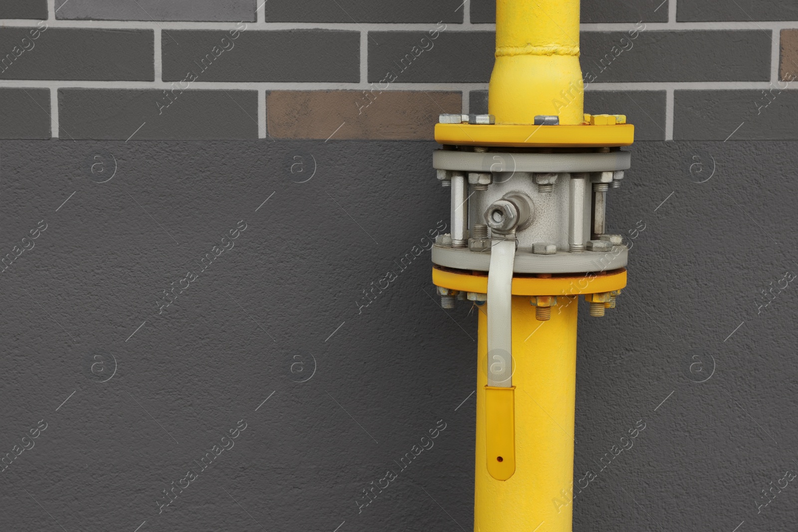 Photo of Yellow gas pipe with valve near brown wall outdoors, space for text