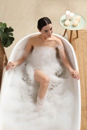 Photo of Beautiful young woman taking bubble bath at home, above view