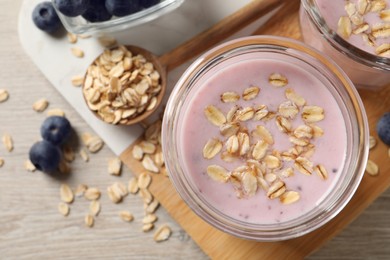 Glass of tasty blueberry smoothie with oatmeal on wooden table, flat lay