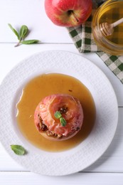 Tasty baked apple with nuts, honey and mint on white wooden table, flat lay