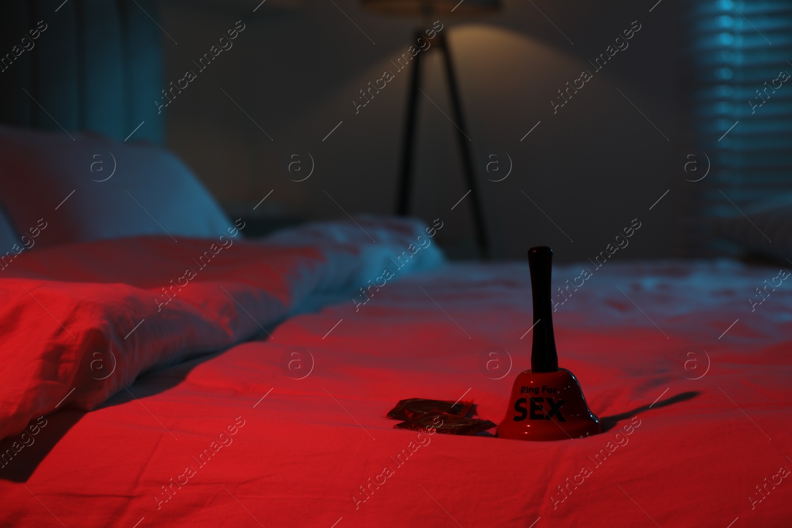 Photo of Ring for sex bell and condoms on bed in bedroom at night