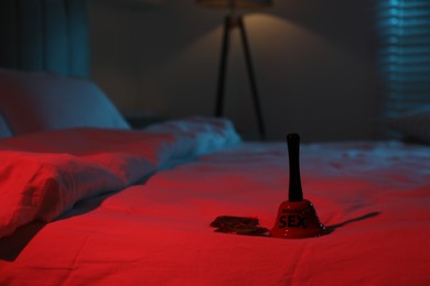 Photo of Ring for sex bell and condoms on bed in bedroom at night