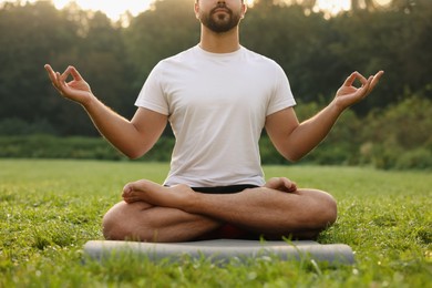 Photo of Man practicing yoga on mat outdoors, closeup. Lotus pose
