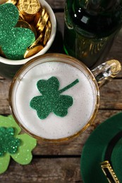 Photo of St. Patrick's day party. Green beer, leprechaun hat, pot of gold and decorative clover leaves on wooden table, flat lay