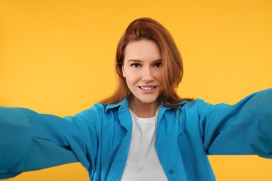 Beautiful woman taking selfie on orange background