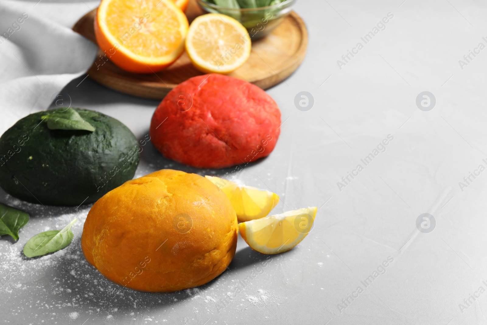 Photo of Dough painted with natural food colorings and ingredients on light grey table. Space for text