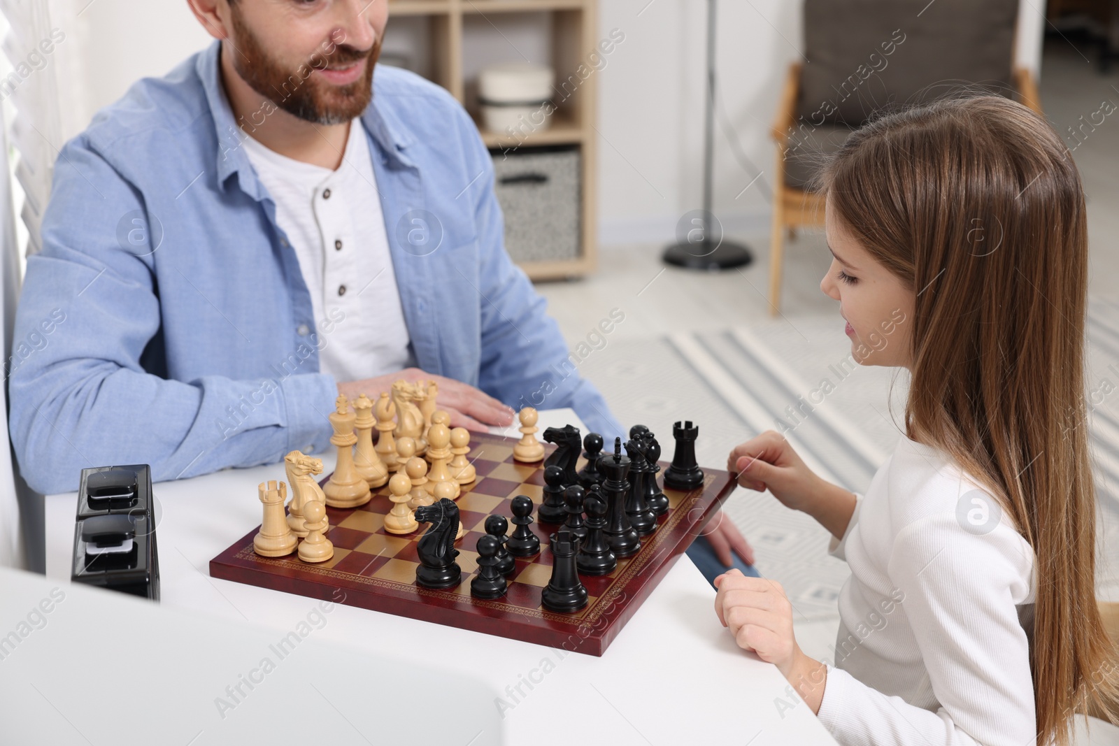 Photo of Father and daughter playing chess at home