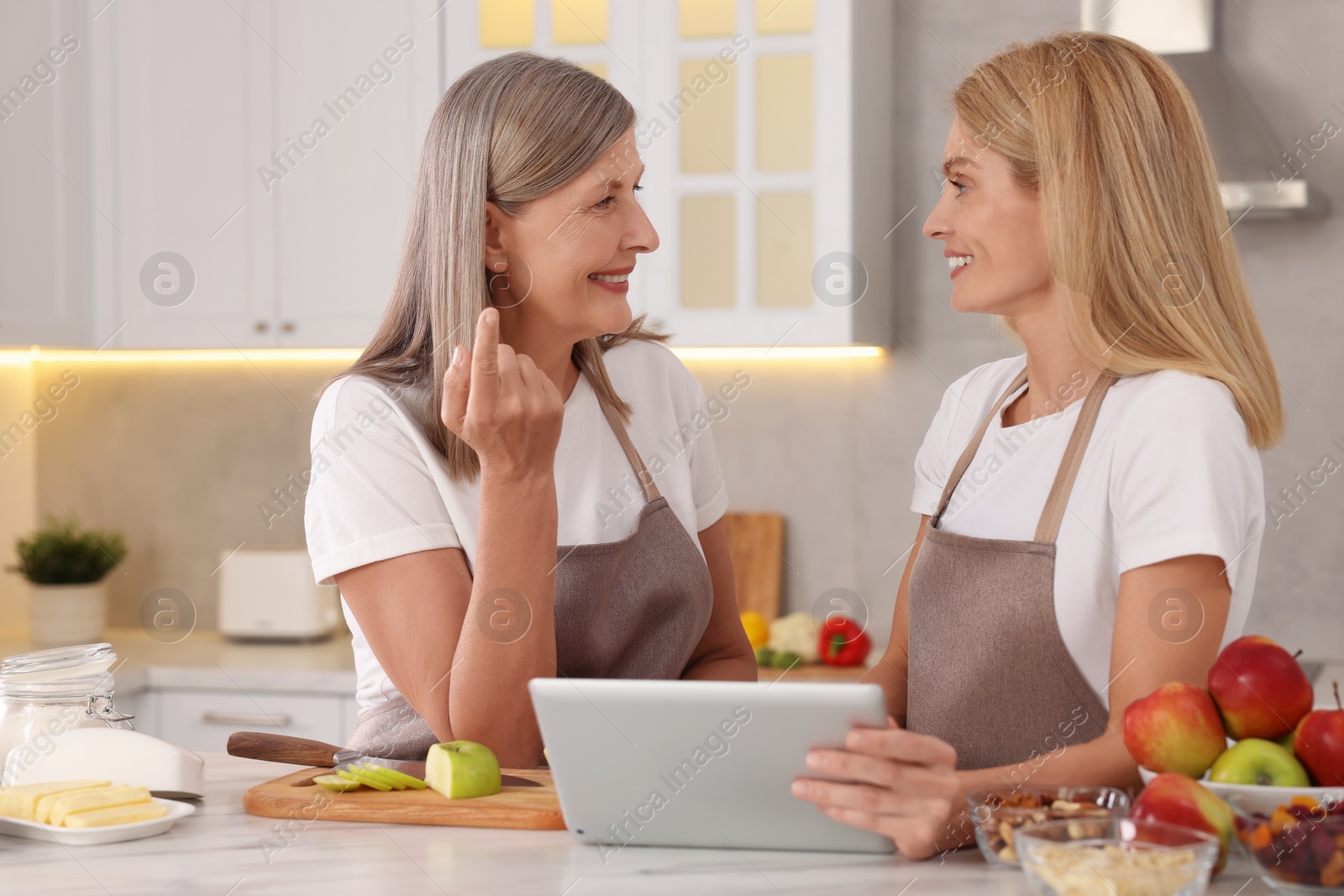 Photo of Happy mature mother and her daughter with tablet in kitchen