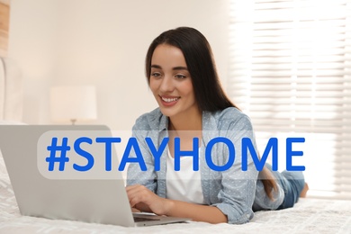 Image of Hashtag Stayhome - protective measure during coronavirus pandemic. Young woman working with laptop on bed