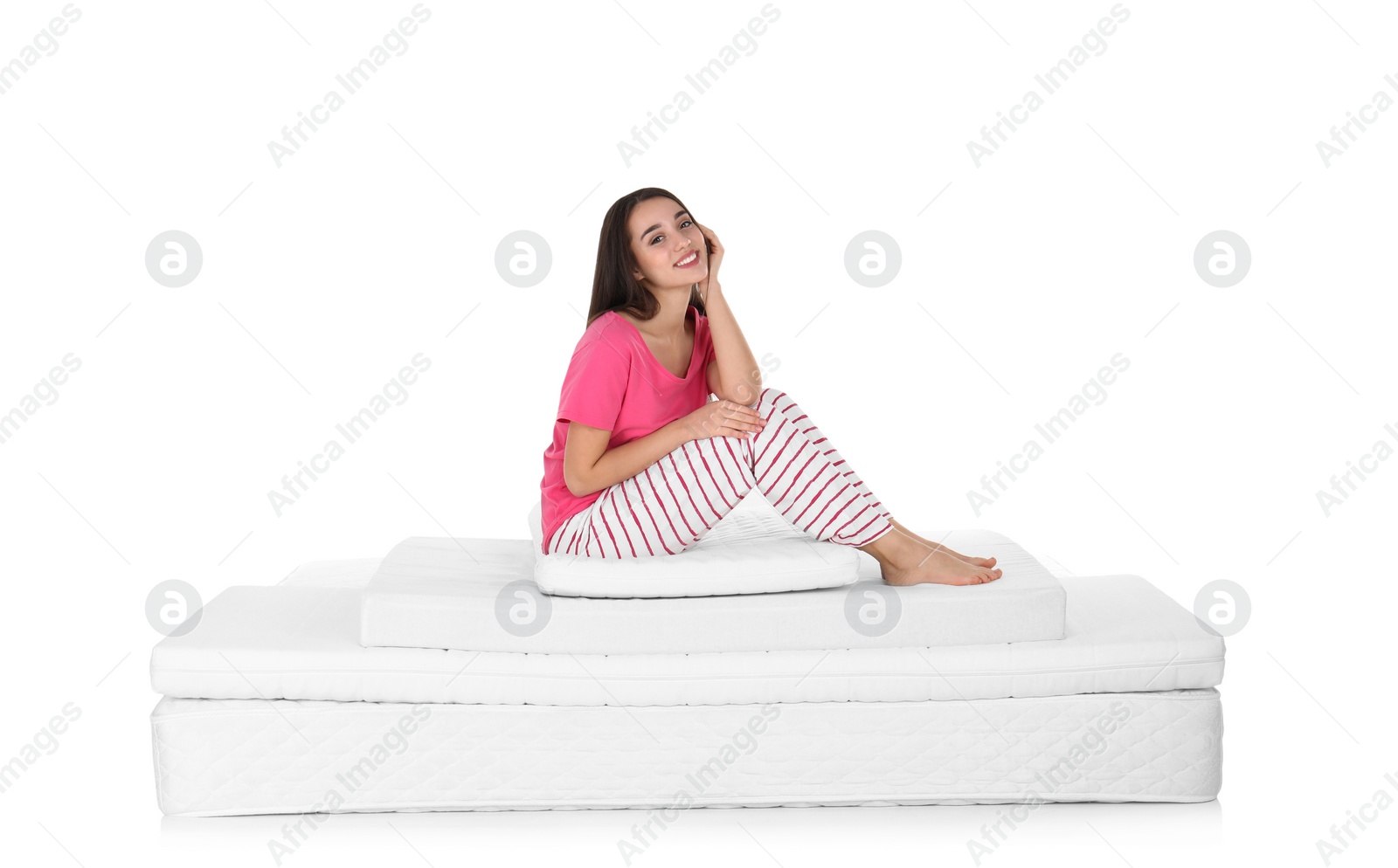 Photo of Young woman sitting on mattress pile against white background